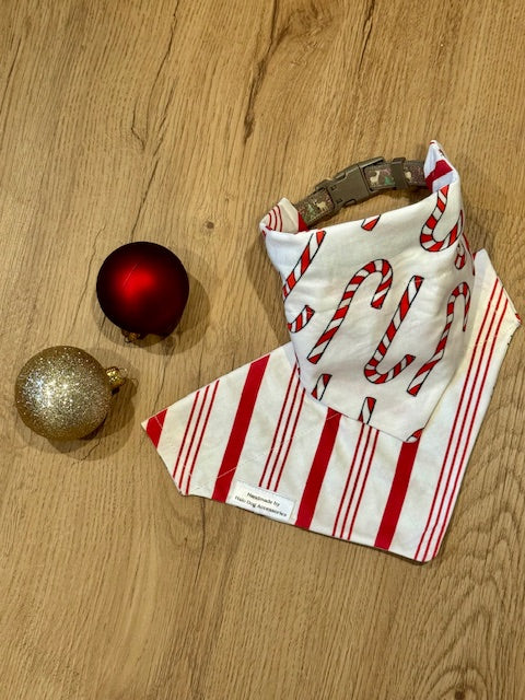 Red and white striped fabric with gold and red Christmas ornaments on a wooden surface