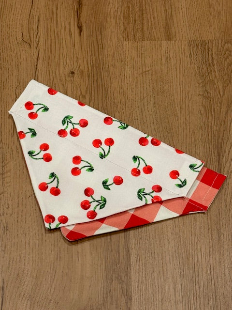 cherries on white background bandana with red and white checkered pattern on the back. 
